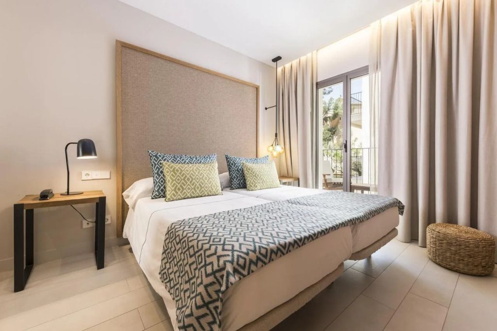 Helles, elegantes Hotelzimmer mit Doppelbett, modernen Dekokissen und großem Fenster.