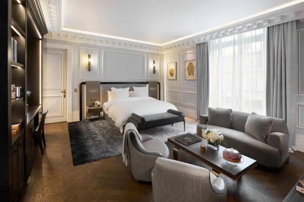 Elegantes Hotelzimmer mit grauer Couch, Doppelbett und stilvoller Dekoration