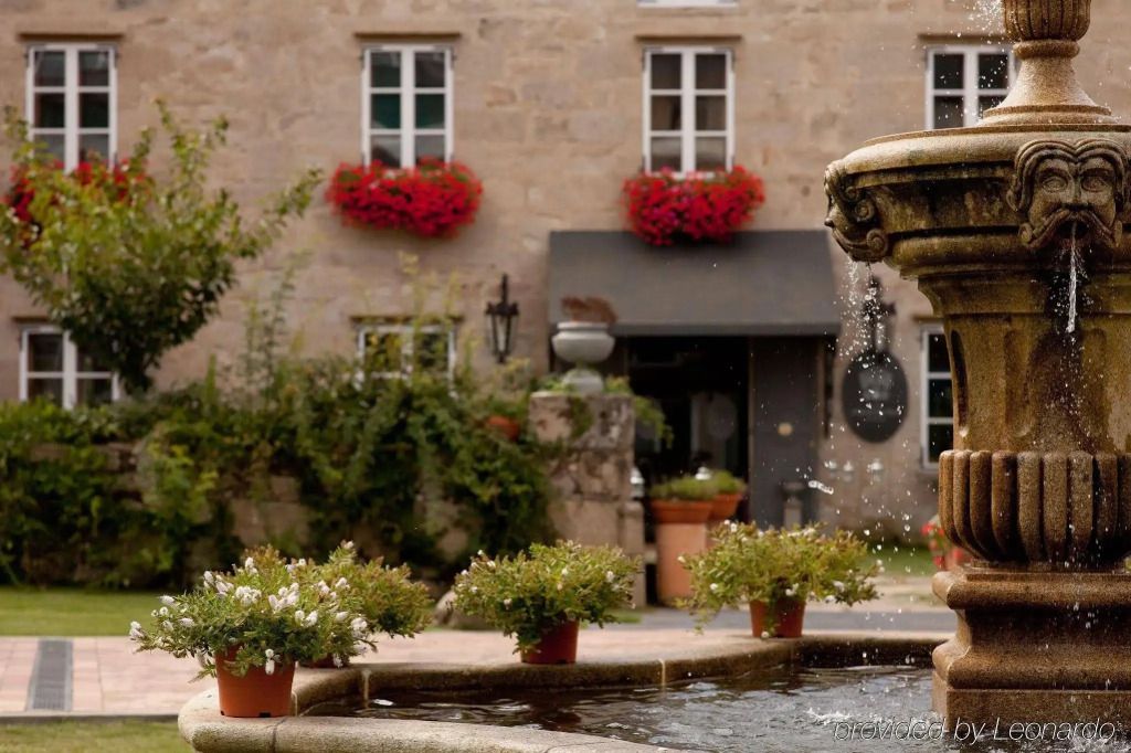 Steinbrunnen im Innenhof des Hotels mit roten Blumen an den Fenstern