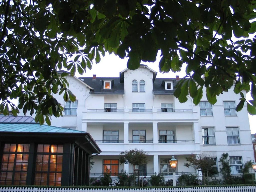 Historische Hotel-Fassade umgeben von Bäumen in einem gepflegten Garten
