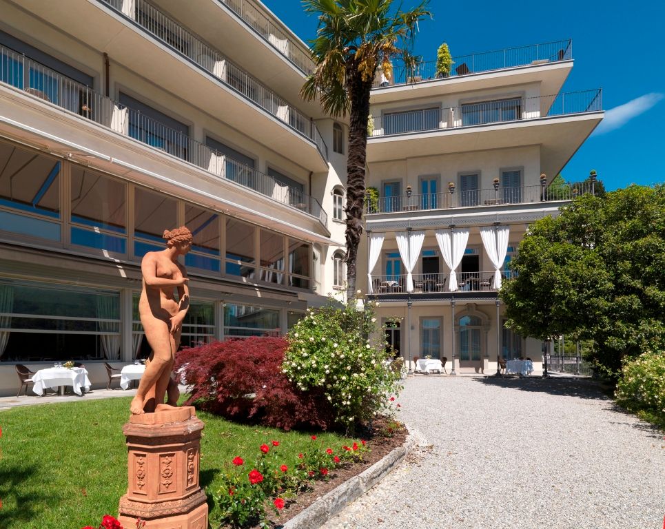 Elegante Fassade des Hotel Villa Flori mit Garten und Skulptur im Vordergrund