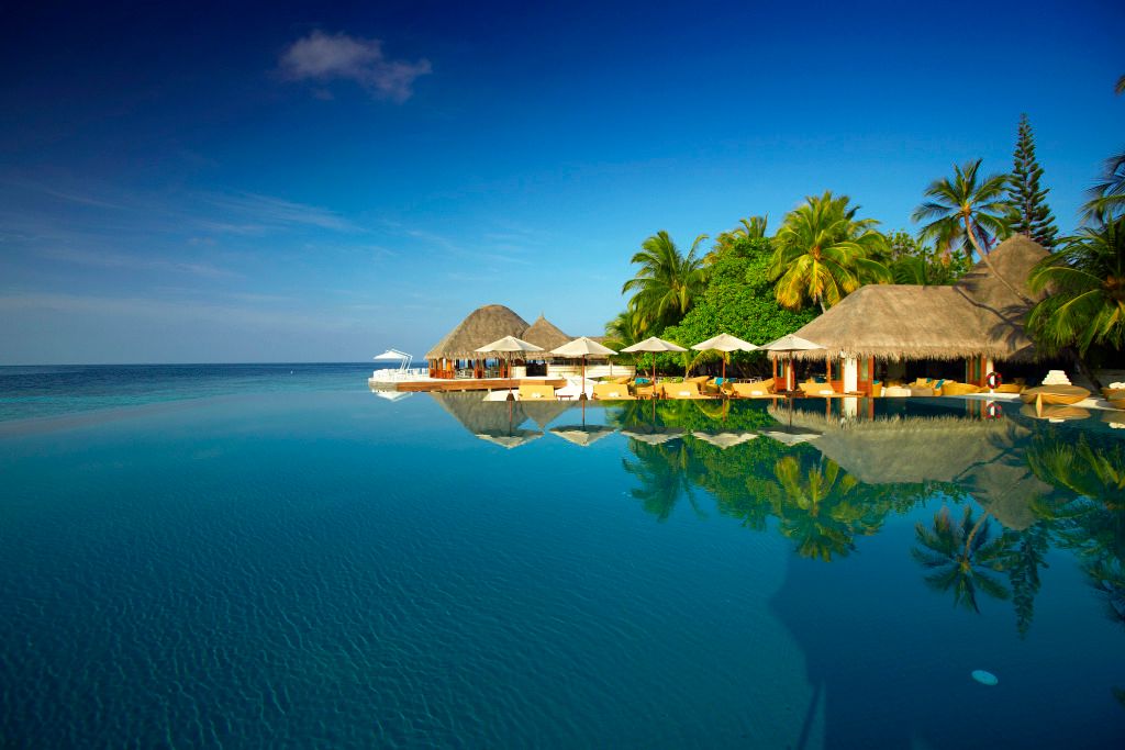 Infinity-Pool mit Blick auf das Meer und Palmen im Huvafen Fushi Maldives