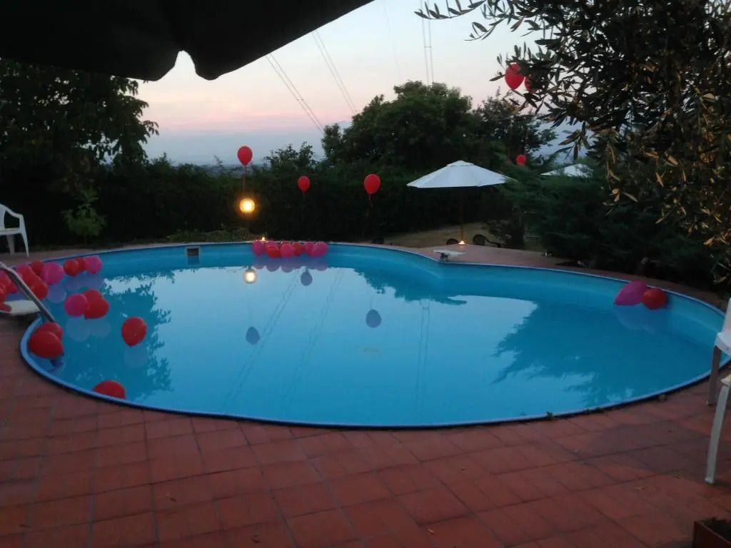 Romantisch dekorierter Außenpool mit rotem Ballons bei Sonnenuntergang