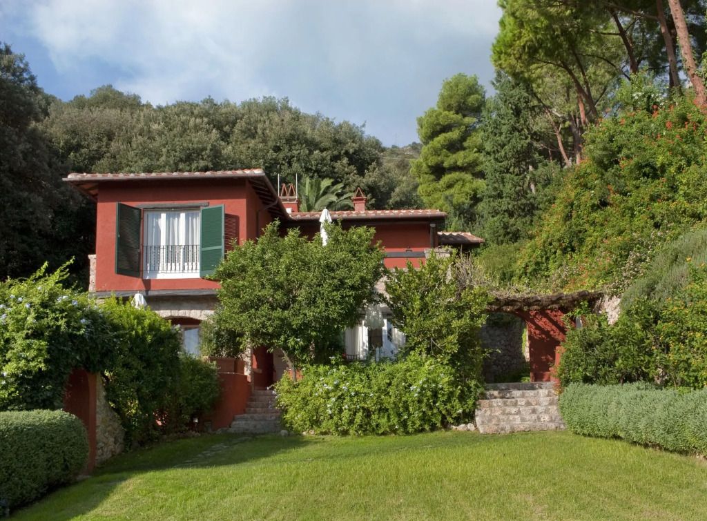 Rote Villa umgeben von üppiger grüner Landschaft im Hotel Il Pellicano