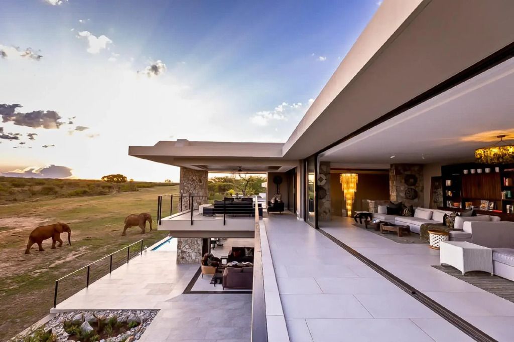 Moderne Architektur der Lodge mit Ausblick auf die Savanne in der Abenddämmerung.