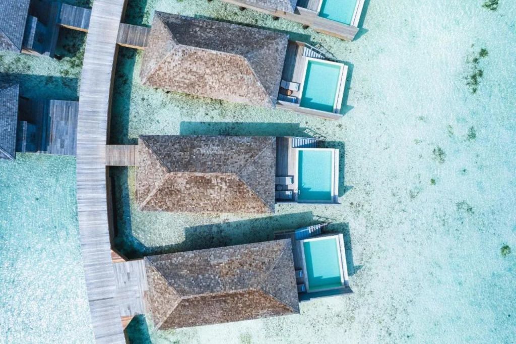 Luftaufnahme von Wasserbungalows mit privaten Pools auf türkisfarbenem Meer