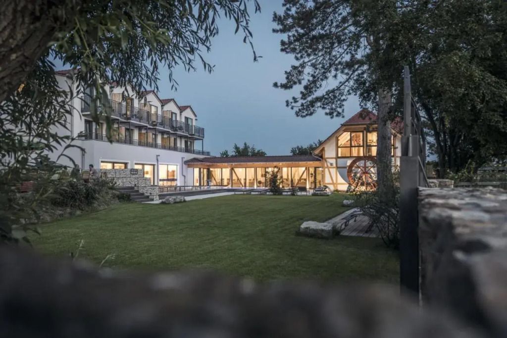 Hotelanlage von außen mit modernem Erweiterungsbau und Fachwerkhaus im Abendlicht