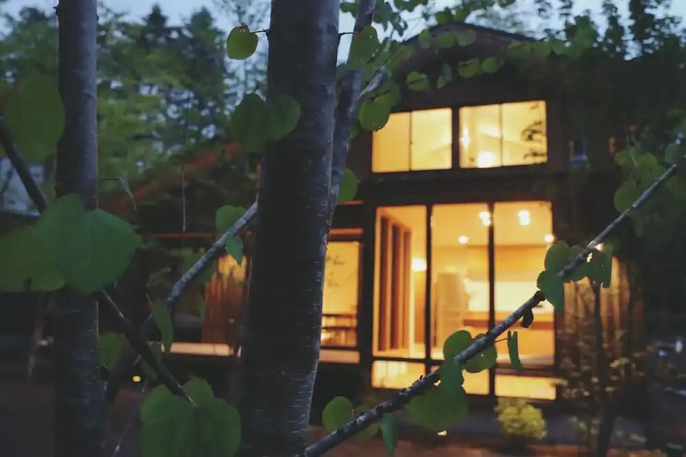 Außenansicht eines modernen Ferienhauses im Wald mit großen Fenstern und stimmungsvoller Beleuchtung