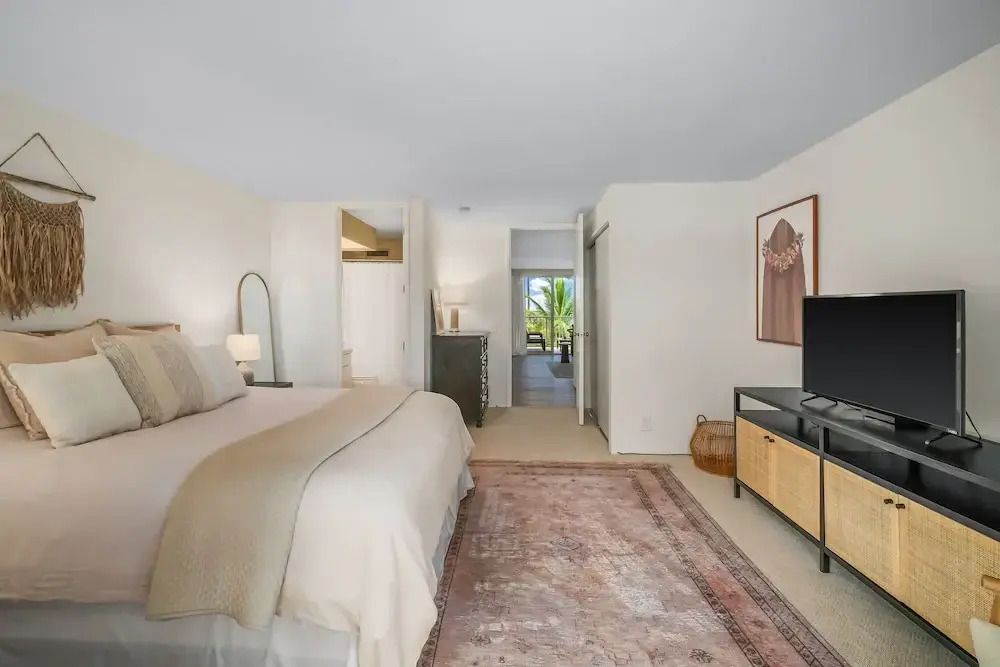 Geräumiges Hotelzimmer mit großem Bett und Teppich, Blick durch die Tür auf die Natur.