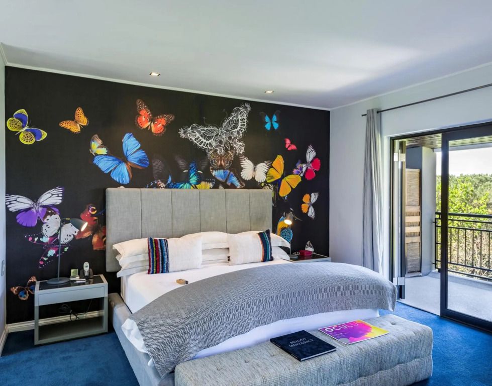 Luxuriöses Schlafzimmer mit Schmetterlingsmotiven an der Wand und großem Bett.
