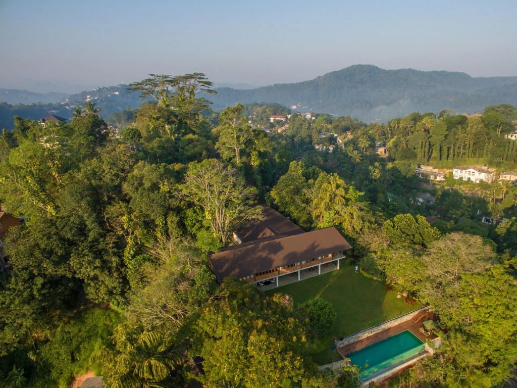 Luftaufnahme des Hotels inmitten üppiger grüner Landschaft mit Pool im Vordergrund