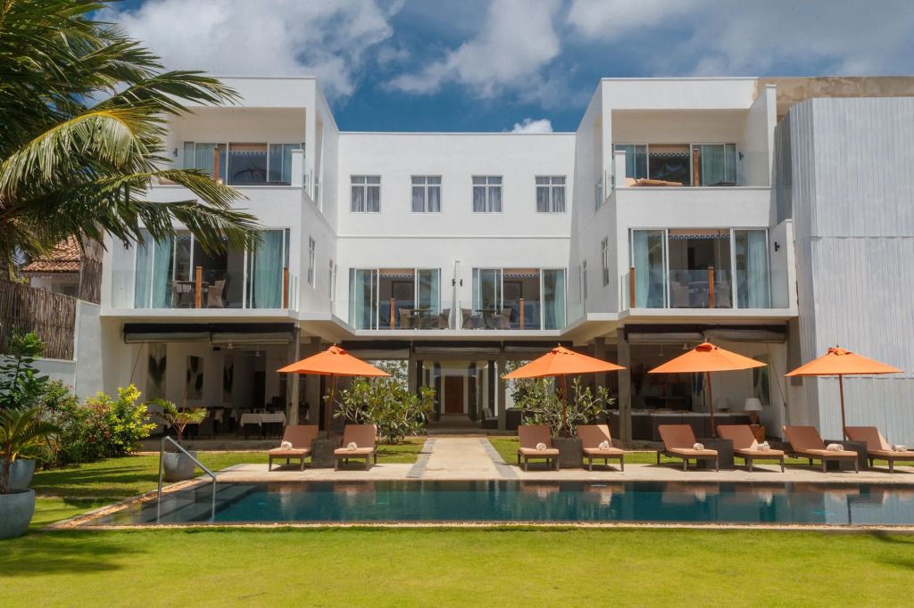 Moderner Hotelpool mit Sonnenliegen und weißen Gebäuden im Hintergrund