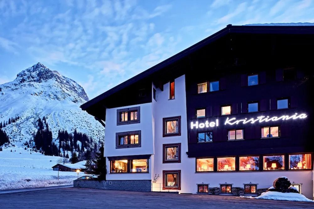 Alpenhotel Fassade bei Abenddämmerung mit leuchtendem Schriftzug
