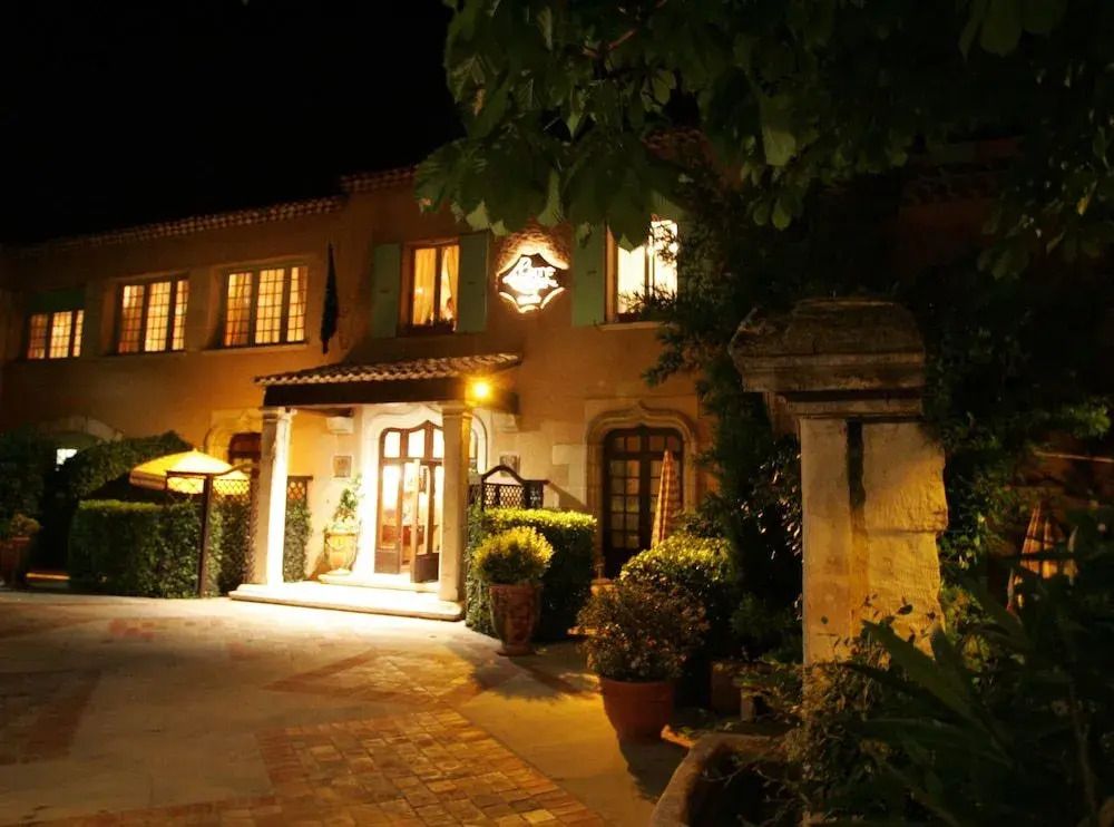 Beleuchtete Hotel-Fassade in der Nacht mit Pflanzen und einladendem Eingang