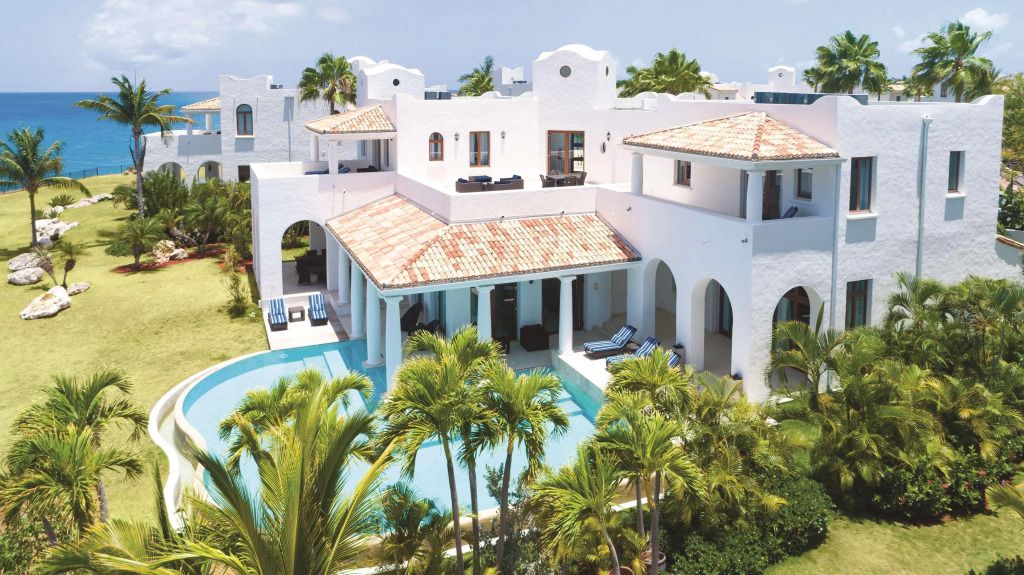 Luxusvilla mit weißer Fassade und privatem Pool umgeben von Palmen