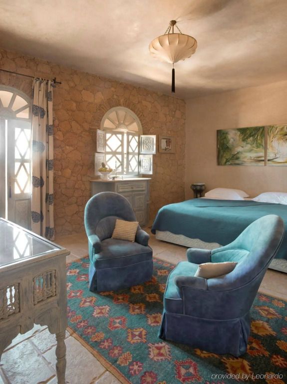 Charmantes Hotelzimmer mit blauen Sesseln und kunstvollem Steindekor.