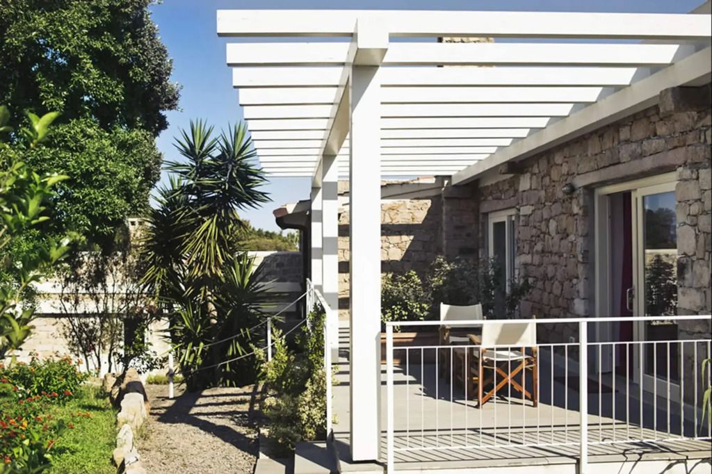 Sonnige Terrasse mit weißen Elementen und grüner Umgebung