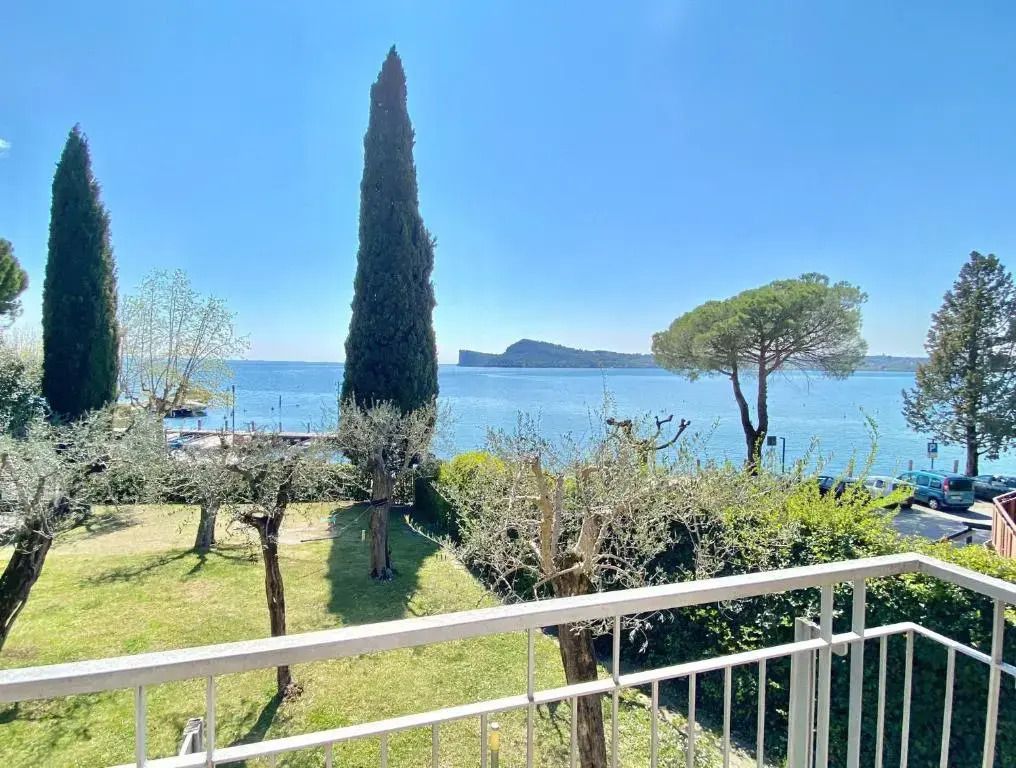 Blick von einem Balkon auf das Meer und grüne Gartenlandschaft