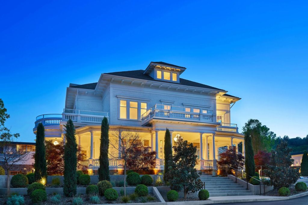 Elegante Hotelvilla in abendlicher Beleuchtung mit schöner Gartenlandschaft.