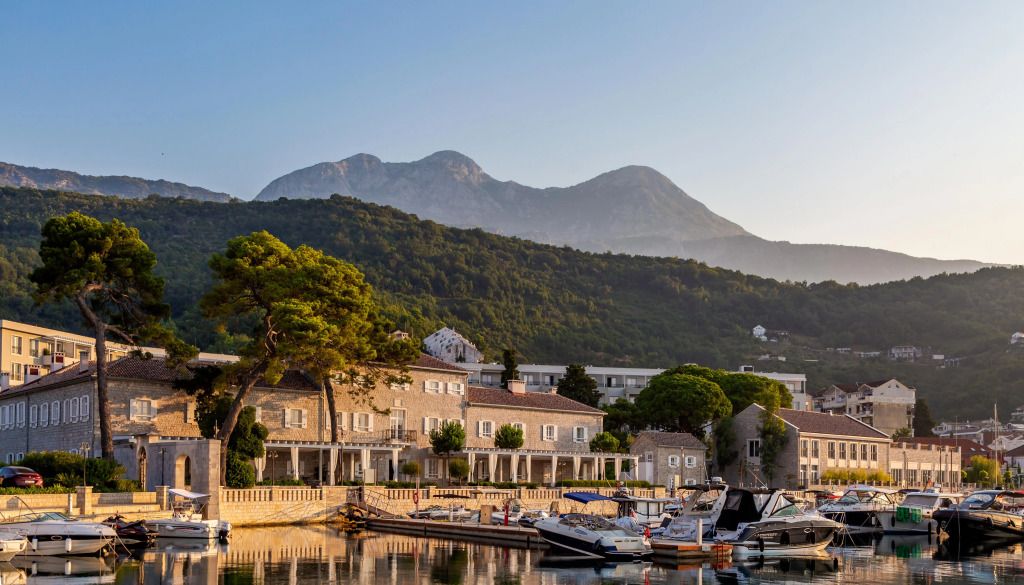Außenansicht von Lazure Hotel mit Bergen im Hintergrund und Yachten im Vordergrund