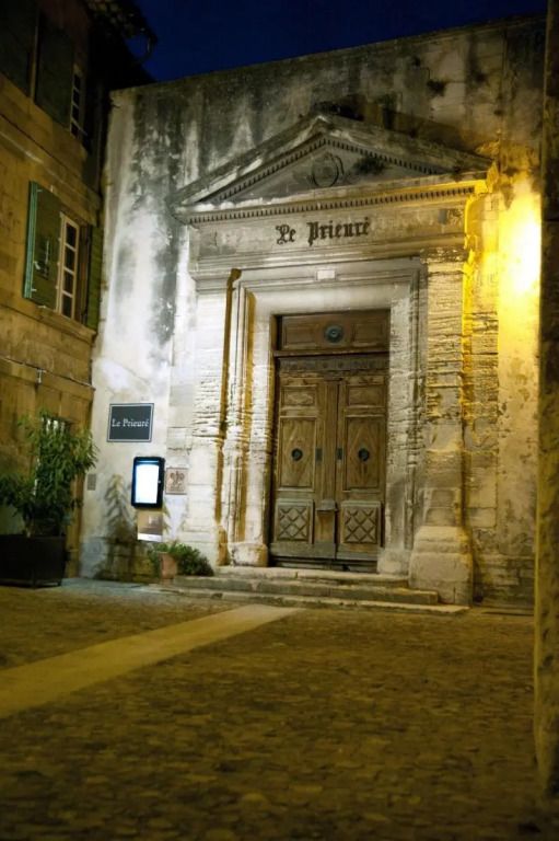 Historische Fassade eines alten Gebäudes mit großer Holztür am Abend beleuchtet.