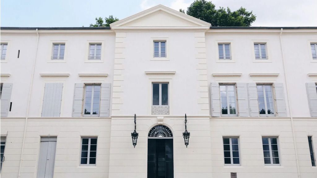 Elegante weiße Fassade eines Hotels mit symmetrischen Fenstern und schwarzen Laternen