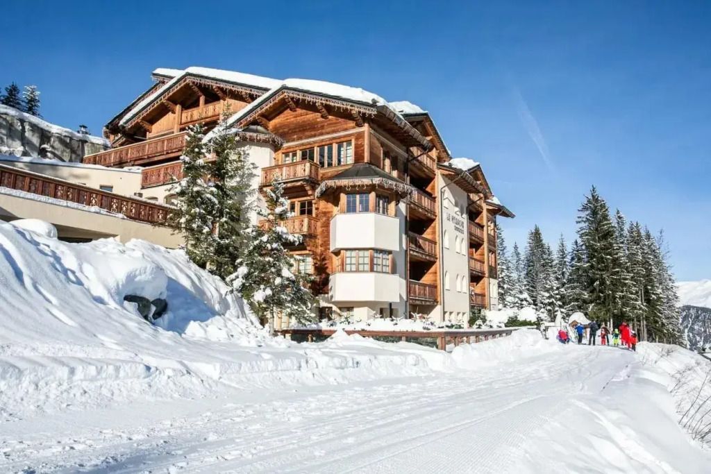 Außenansicht des Hôtel Le Strato im Winter mit verschneiten Dächern