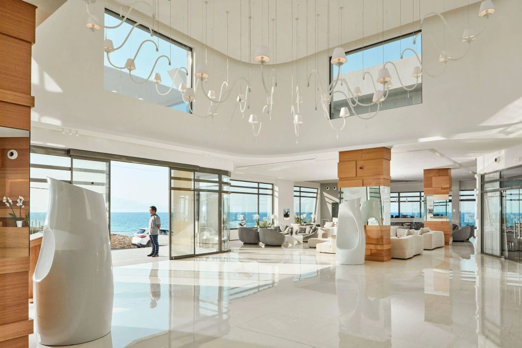 Helle Lobby mit modernem Design und Blick auf das Meer durch Glaswände.