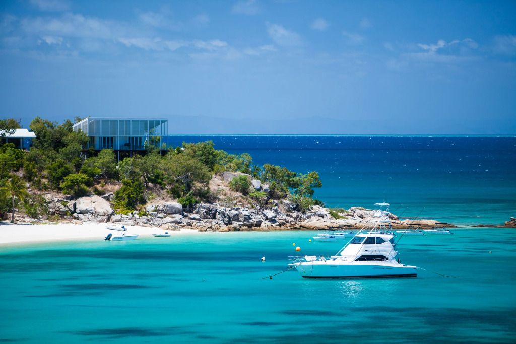 Türkises Meer und weiße Yacht bei felsiger Küste unter blauem Himmel