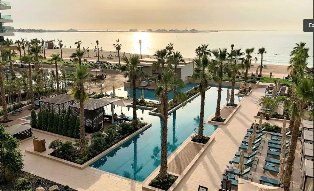 Infinity-Pool mit Blick auf den Strand und Palmen in Dubai bei Sonnenuntergang