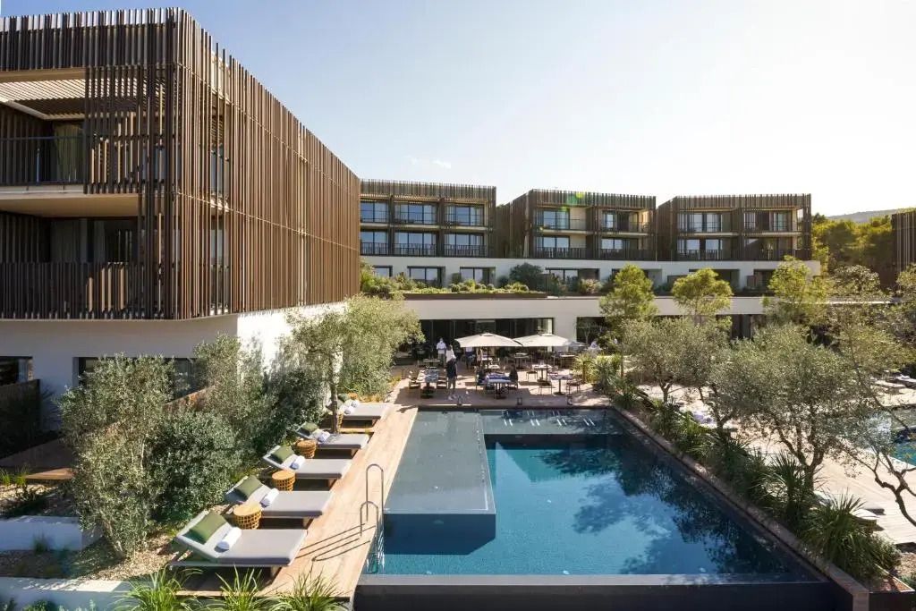 Moderner Hotelpool mit Liegen und architektonisch ansprechendem Gebäude