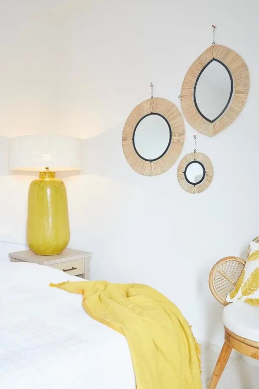 Elegantes Hotelzimmer mit gelbem Dekor und runden Spiegeln an der Wand.