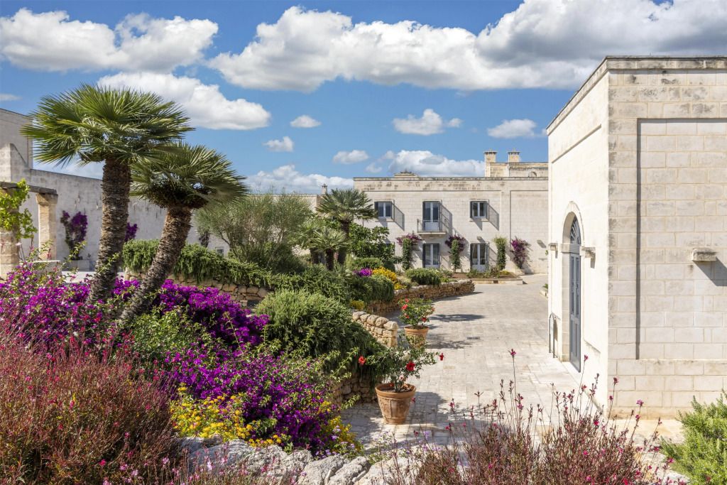 Mediterraner Garten mit blühenden Pflanzen und traditioneller Architektur unter blauem Himmel