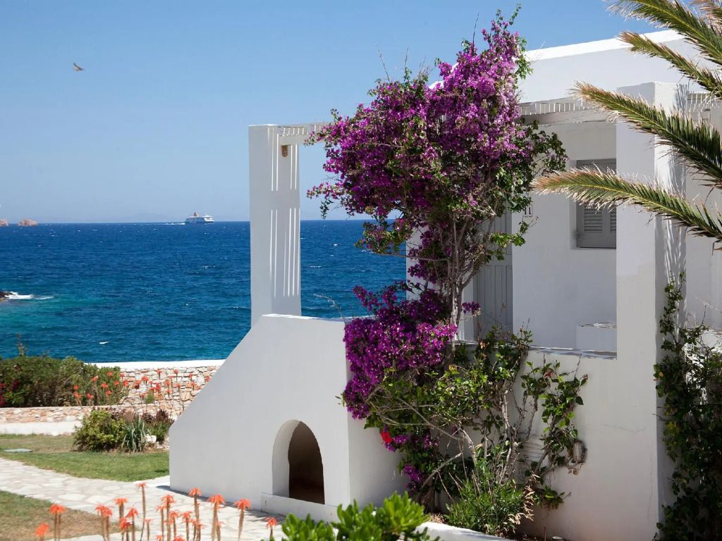 Weißes Gebäude mit violetter Bougainvillea und Meer im Hintergrund