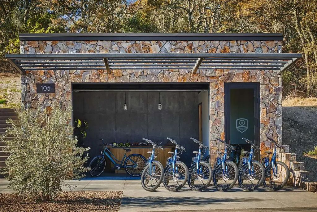 Fahrradverleihstation des Hotels mit blauen Fahrrädern vor einer gemauerten Wand.