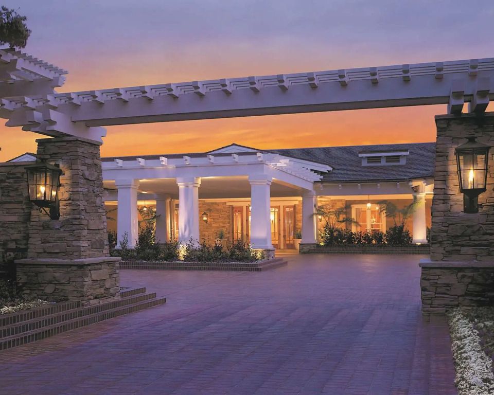 Elegante Hotelfassade bei Sonnenuntergang mit weißen Säulen und einladendem Eingang.