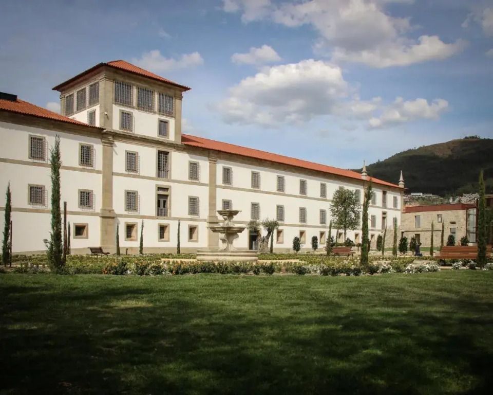 Historische Fassade des Hotels mit gepflegtem Garten und Bergkulisse.