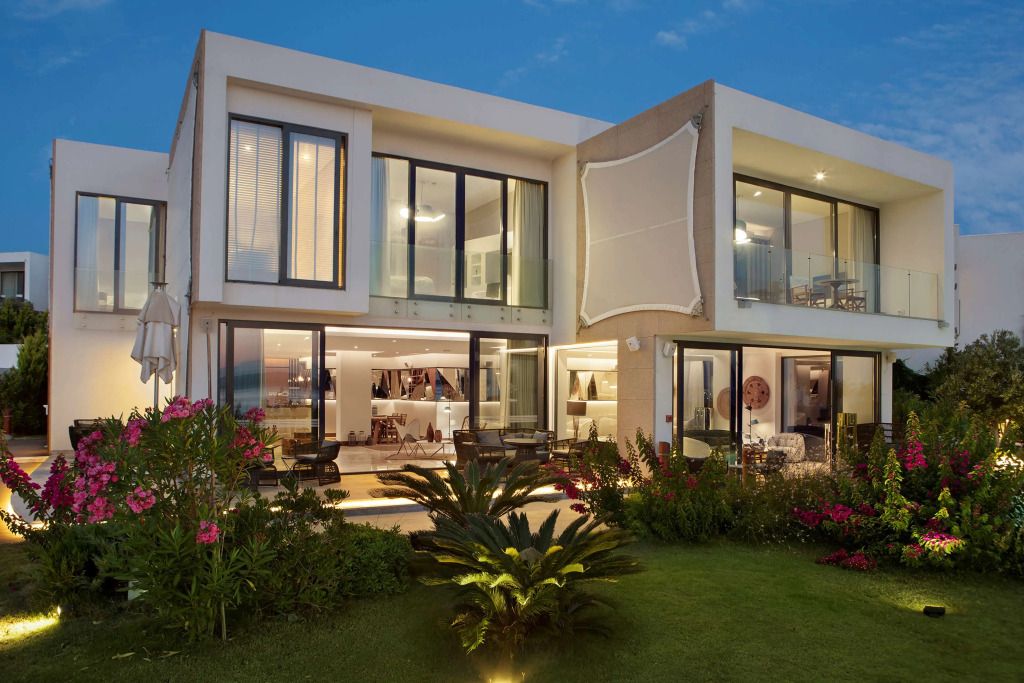 Moderne Villa mit großen Fenstern und gepflegtem Garten bei Dämmerung