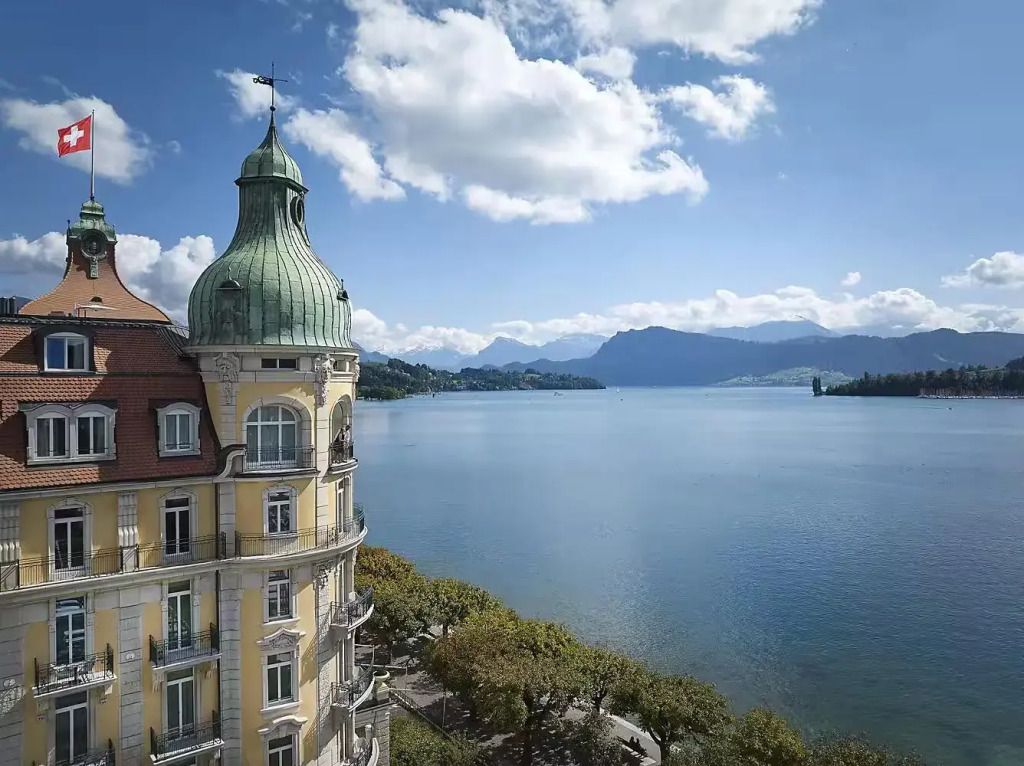 Majestätische Hotelarchitektur vor malerischer Seelandschaft mit Bergen.