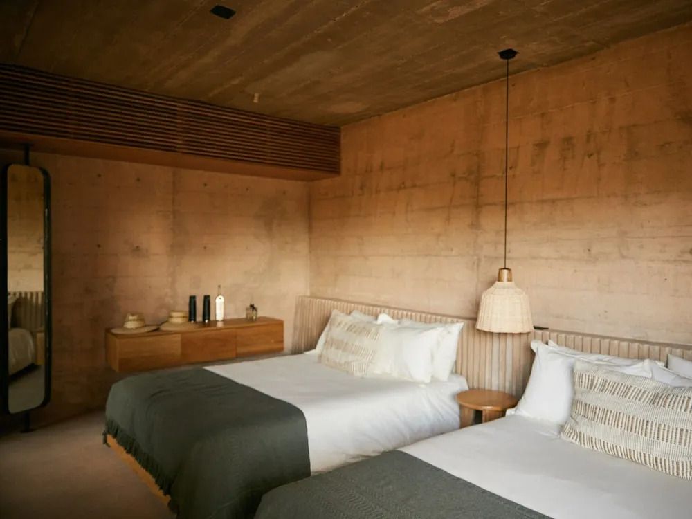 Geräumiges Hotelzimmer mit zwei Doppelbetten in warmen Erdtönen