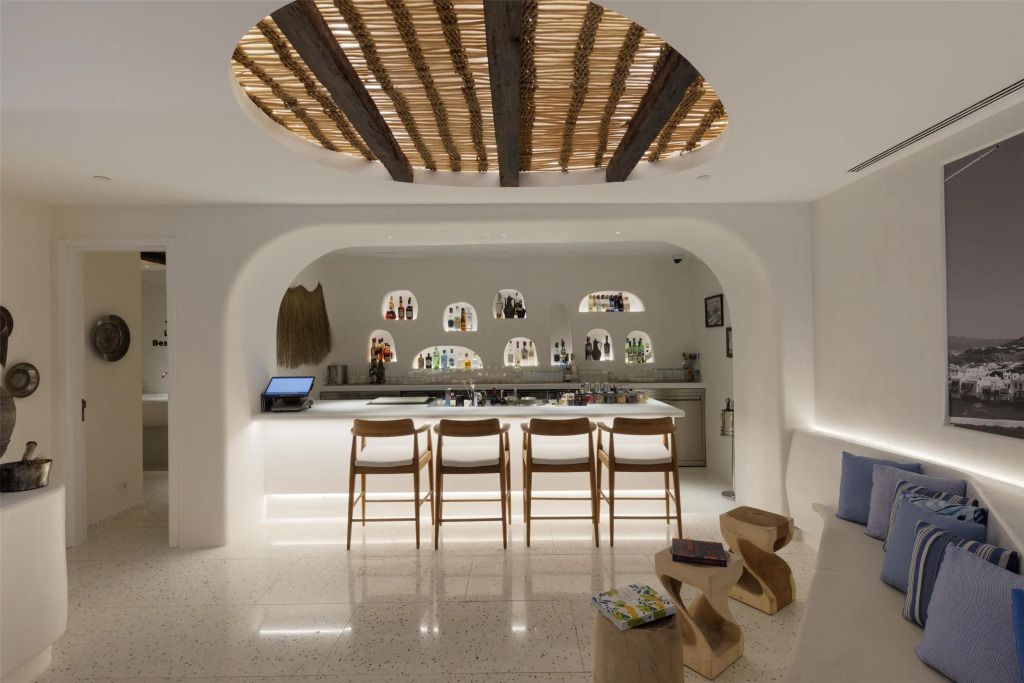 Barbereich mit hölzernen Barhockern und beleuchtetem Tresen