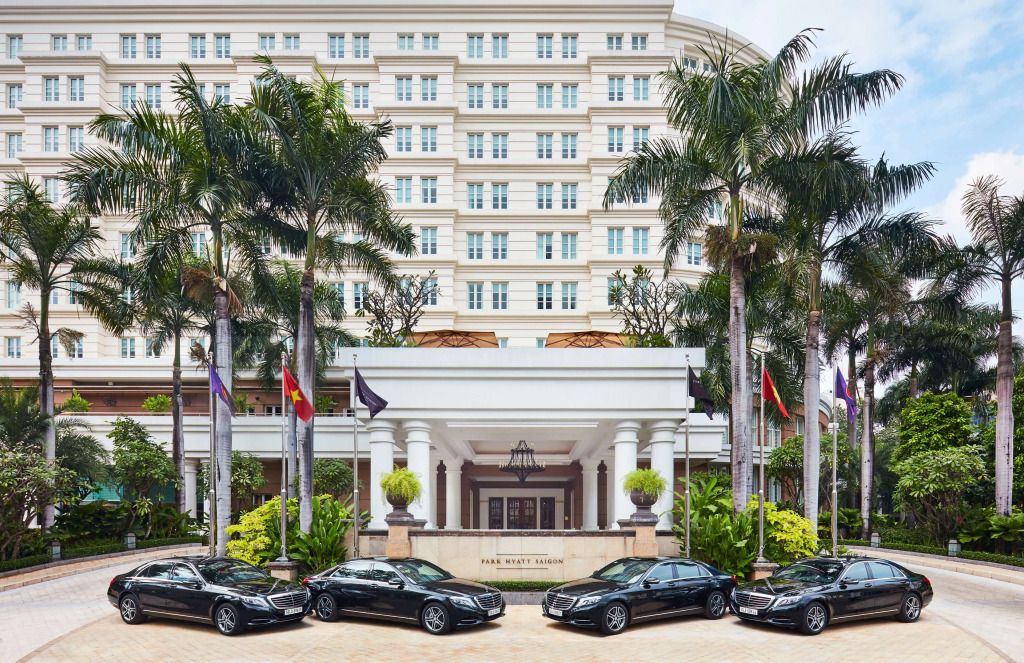 Elegante Fassade des Park Hyatt Saigon mit Palmen und Luxusautos im Vordergrund