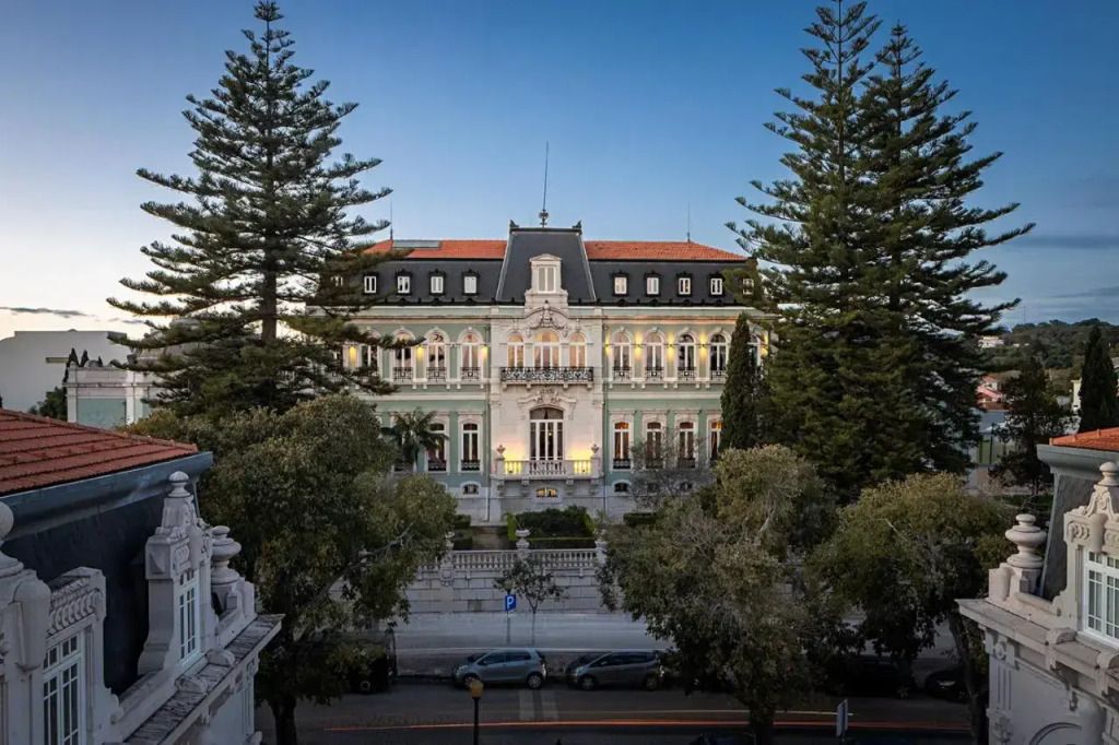 Außenansicht des Pestana Palace Lisboa von Bäumen gesäumt bei Abenddämmerung