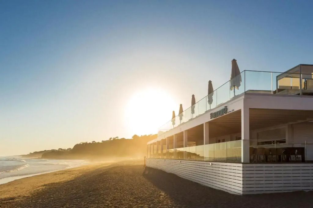 Strandrestaurant mit Sonnenschirmen bei Sonnenuntergang
