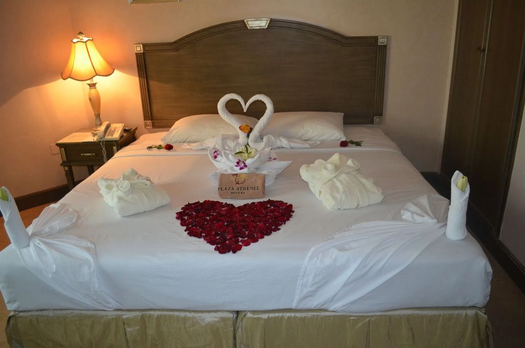 Bett mit Rosenblättern in Herzform und Handtuch-Schwänen