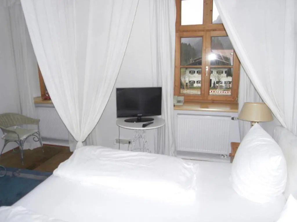 Elegantes Hotelzimmer mit weißen Vorhängen und Blick auf traditionelle Fenster