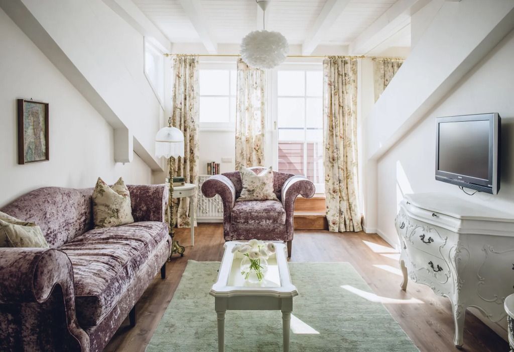 Gemütliches Wohnzimmer in heller Dachgeschoss-Suite mit eleganten Möbeln und floralen Vorhängen