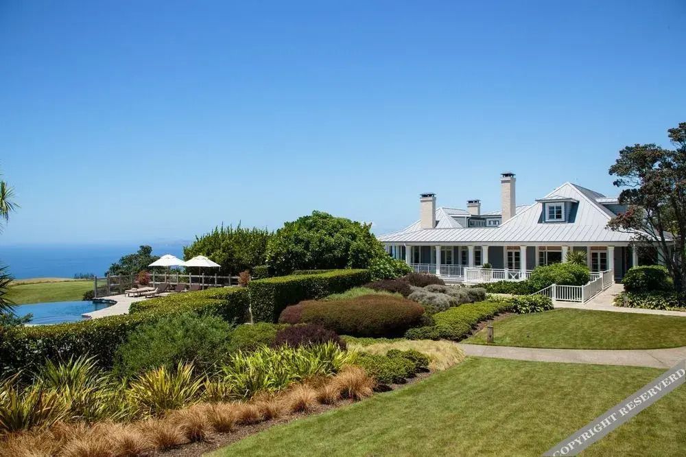 Luxuriöse Hotelanlage mit gepflegtem Garten und Blick auf den Ozean an einem sonnigen Tag