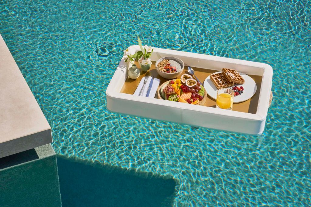 Schwimmendes Frühstückstablett im Pool mit Obst und Waffeln