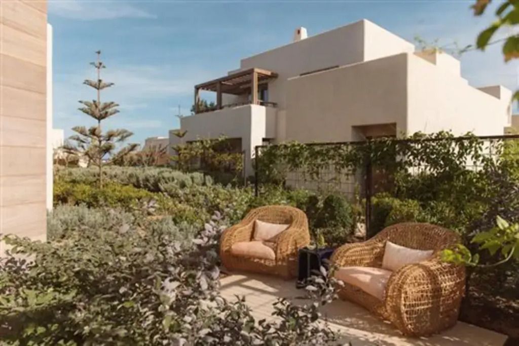 Gartenbereich mit Rattan-Sesseln vor moderner Villa